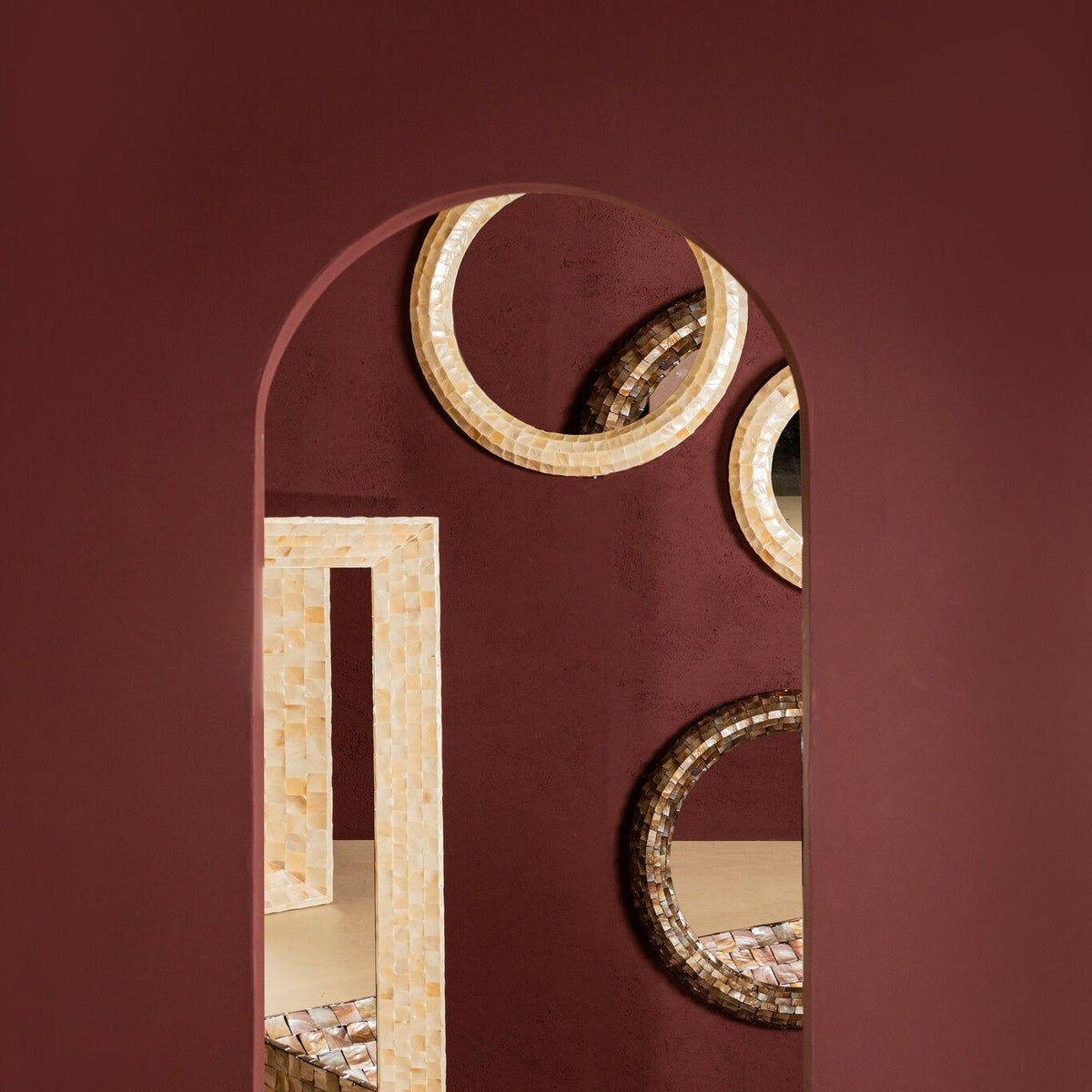 Chelsae spiegels van PTMD in een sfeervolle opstelling tegen een bordeauxrode wand