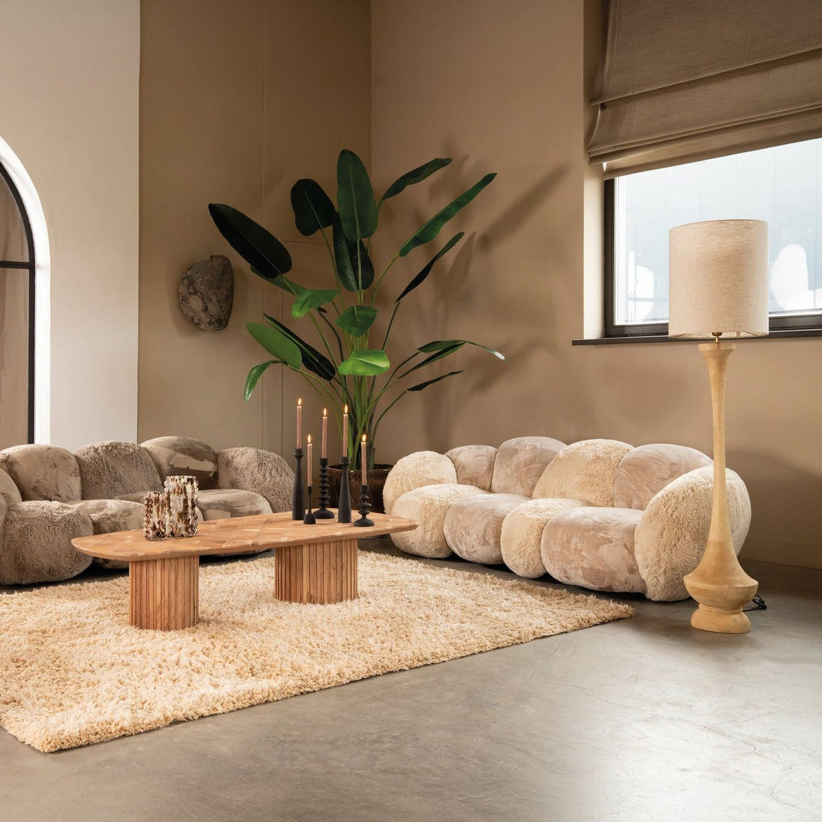 Ruime woonkamer met de beige Curvae bank van PTMD, houten salontafel en groot vloerkleed