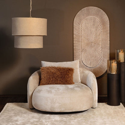 Devi hanglamp in taupe van PTMD boven een ronde fauteuil in een warme woonkamer