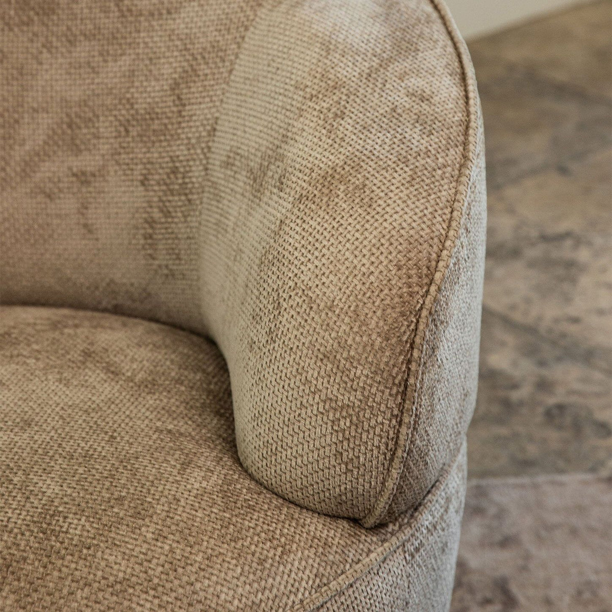 Detail van de zachte beige Eden stof en de ronde armleuning van de Filou fauteuil