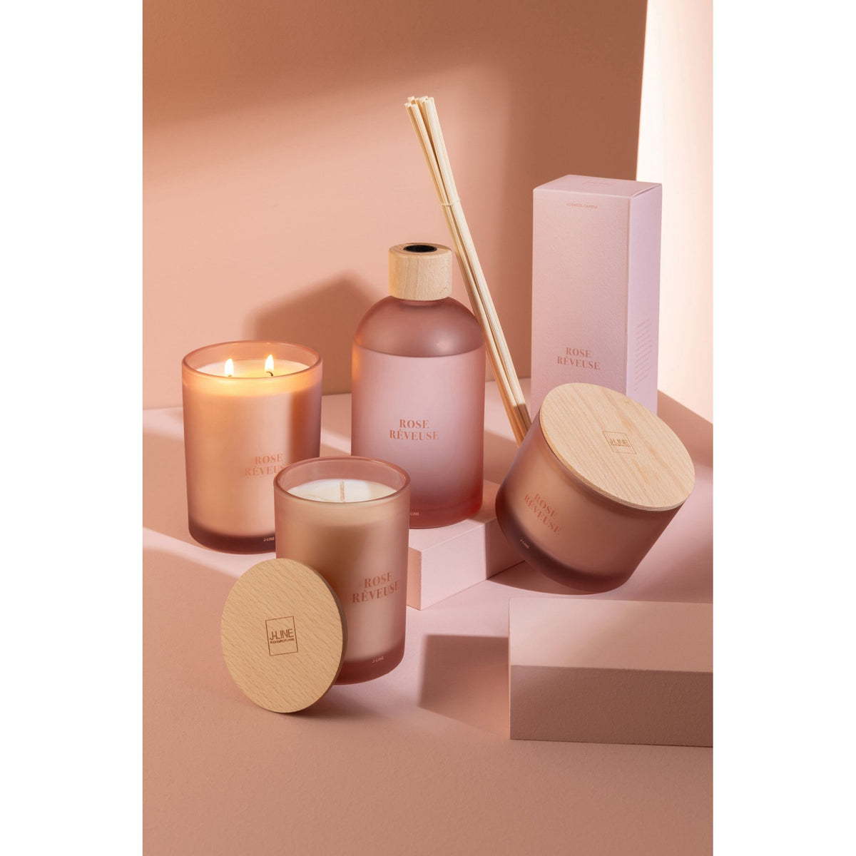 Geurkaars Accords Essentiels Rose Rêveuse 38 Uur van J-Line op decoratieve blokken in een warme sfeerfoto