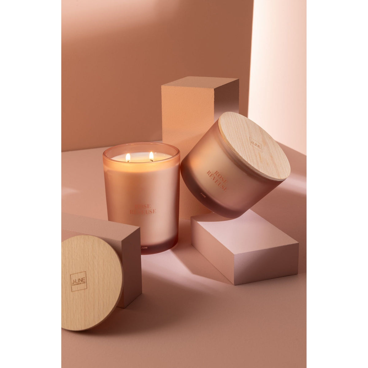 Geurkaars Accords Essentiels Rose Rêveuse 52 Uur van J-Line op decoratieve blokken in een warme sfeerfoto