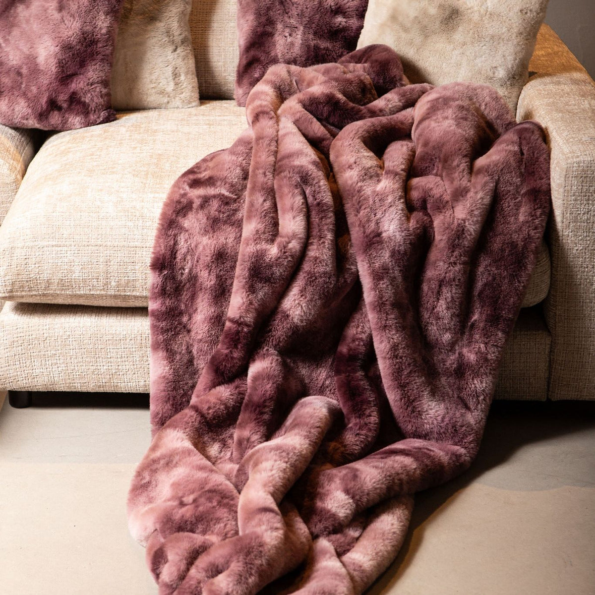 Linde Plaid Burgundy Fluweel 150x200cm van PTMD, burgundy plaid gedrapeerd over een bank met bijpassende kussens