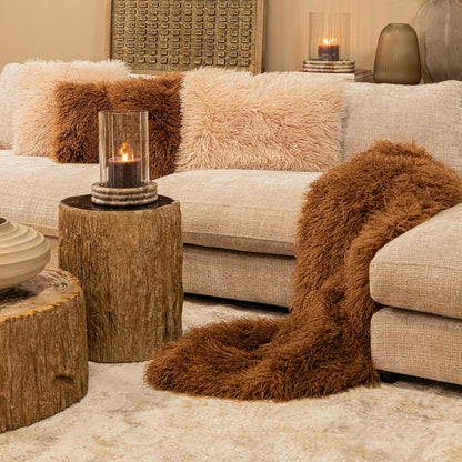 Rexx donkerbruine imitatiebont plaid S van PTMD, gestyled met kussens in een warme interieursetting