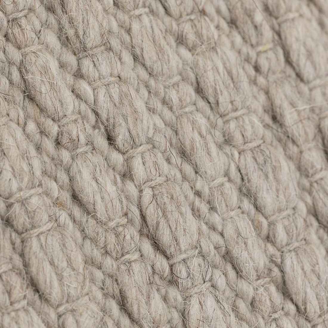 Vloerkleed Nirvana van MUST Living, detailfoto van de dikke gevlochten wolstructuur in beige