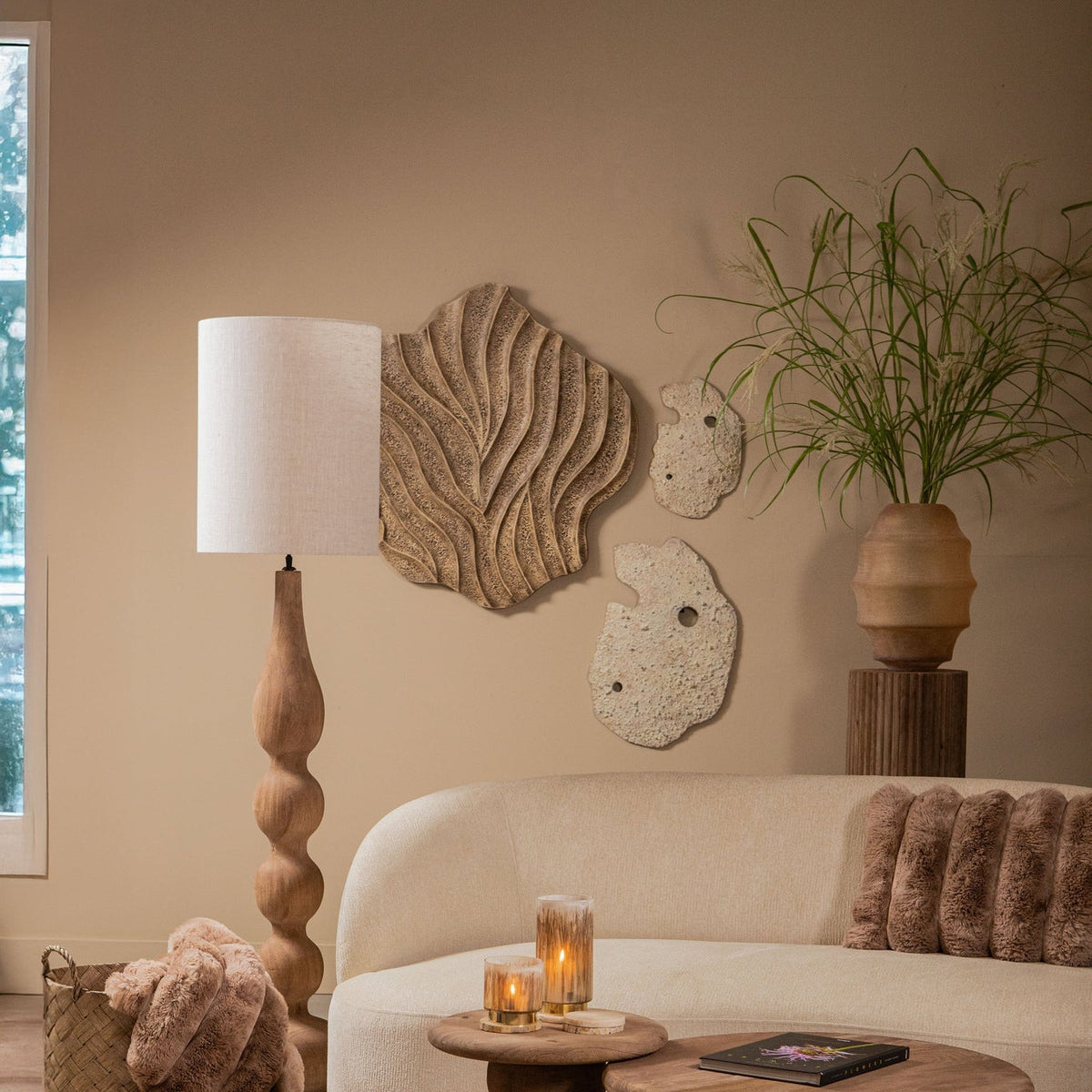 Woonkamer met Abbie wandpanelen van PTMD boven een lichte bank, met staande lamp en salontafels