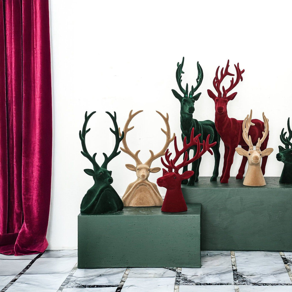 Yule Rendierkop Beige Large van PTMD, rendieren en kerstboompjes in drie kleuren op een groene kast